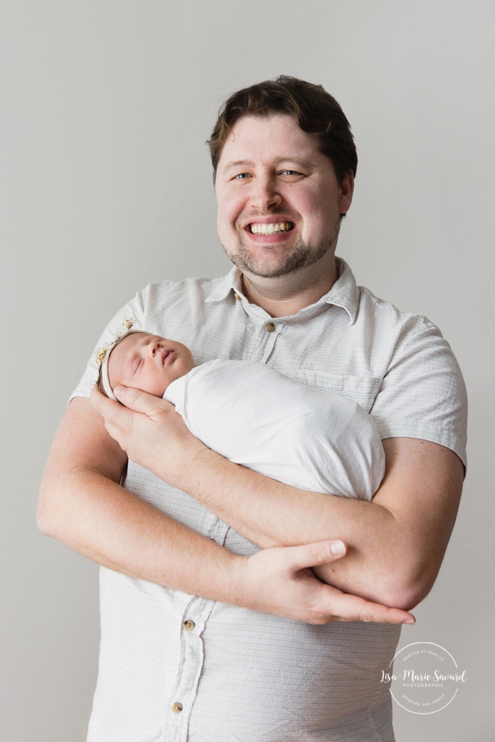 Dad holding newborn baby. Minimalist newborn photos. Clean newborn photos. Photographie de nouveau-né à Montréal. Montreal newborn photography. Séance photo bébé naissant Montréal. Montreal newborn baby photoshoot.