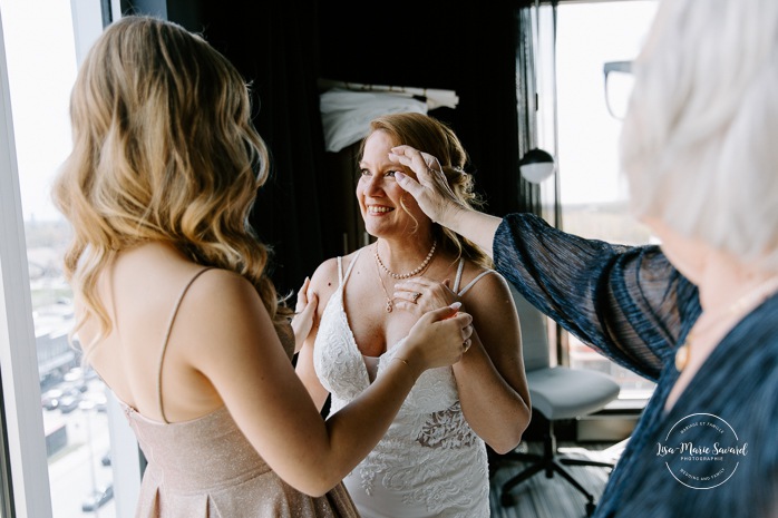 Bride getting ready with mother and daughter in hotel room. Mariage Grand Times Hotel Laval. Mariage à Laval. Laval Grand Times Hotel wedding. Laval wedding photographer.