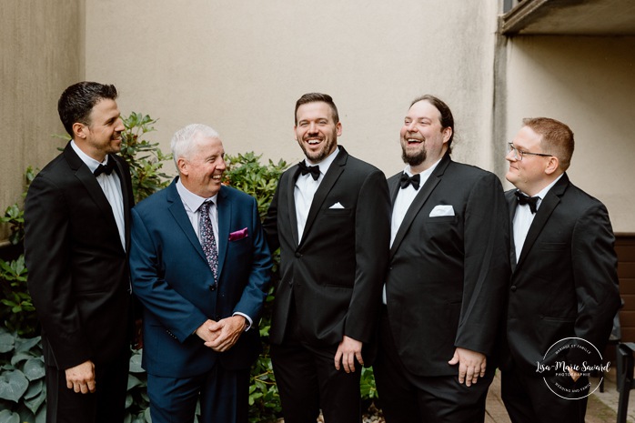 Groom getting ready with groomsmen in hotel room. Mariage Hôtel Rive-Gauche Beloeil. Photographe mariage à Montréal. Montreal wedding photographer.