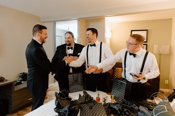 Groom getting ready with groomsmen in hotel room. Mariage Hôtel Rive-Gauche Beloeil. Photographe mariage à Montréal. Montreal wedding photographer.