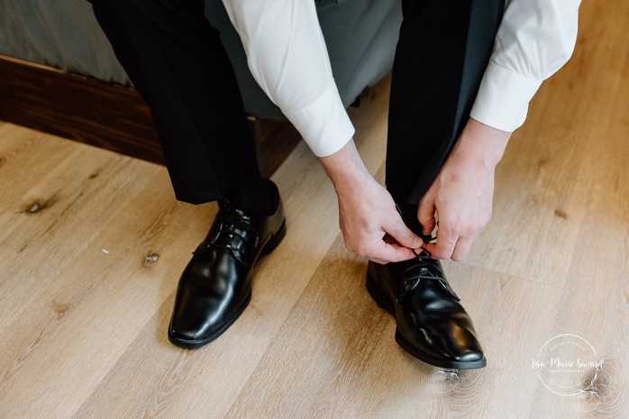 Groom getting ready with groomsmen in hotel room. Mariage Hôtel Rive-Gauche Beloeil. Photographe mariage à Montréal. Montreal wedding photographer.