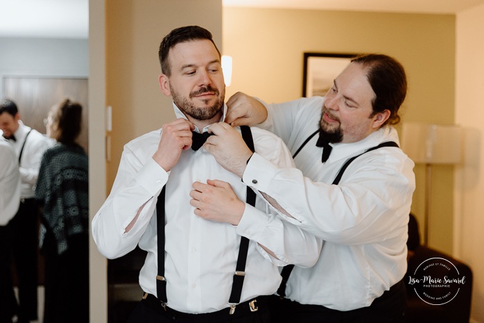 Groom getting ready with groomsmen in hotel room. Mariage Hôtel Rive-Gauche Beloeil. Photographe mariage à Montréal. Montreal wedding photographer.