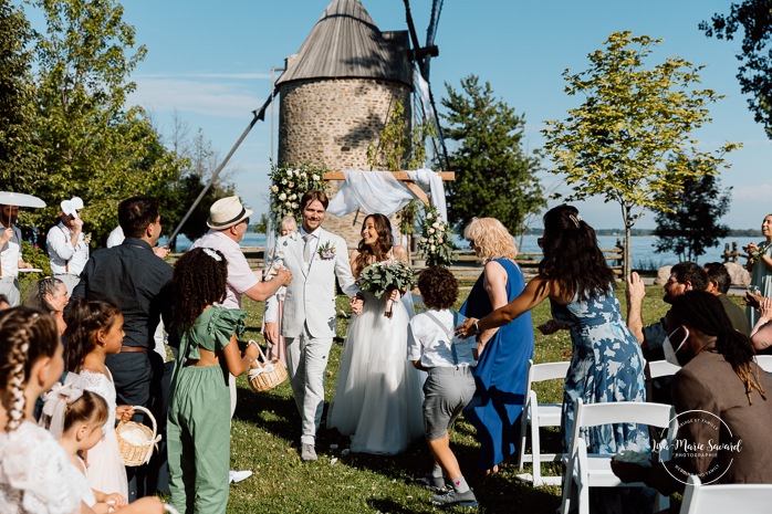 Outdoor wedding ceremony in front of windmill. Mariage à la Pointe-du-Moulin. Photographe mariage à Montréal. Pointe-du-Moulin wedding. Montreal wedding photographer.