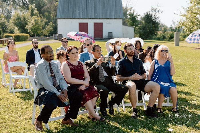 Outdoor wedding ceremony in front of windmill. Mariage à la Pointe-du-Moulin. Photographe mariage à Montréal. Pointe-du-Moulin wedding. Montreal wedding photographer.