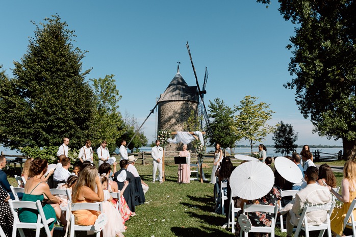 Outdoor wedding ceremony in front of windmill. Mariage à la Pointe-du-Moulin. Photographe mariage à Montréal. Pointe-du-Moulin wedding. Montreal wedding photographer.