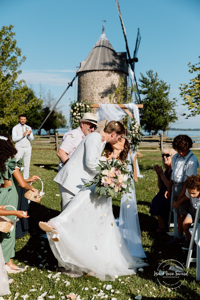 Outdoor wedding ceremony in front of windmill. Mariage à la Pointe-du-Moulin. Photographe mariage à Montréal. Pointe-du-Moulin wedding. Montreal wedding photographer.