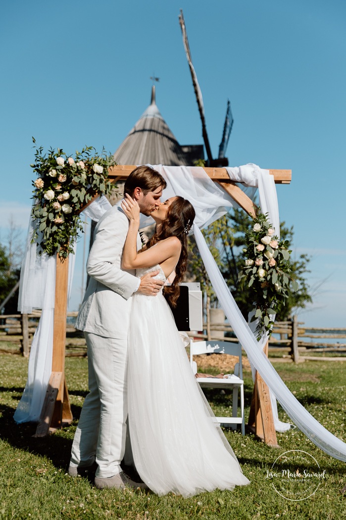 Outdoor wedding ceremony in front of windmill. Mariage à la Pointe-du-Moulin. Photographe mariage à Montréal. Pointe-du-Moulin wedding. Montreal wedding photographer.