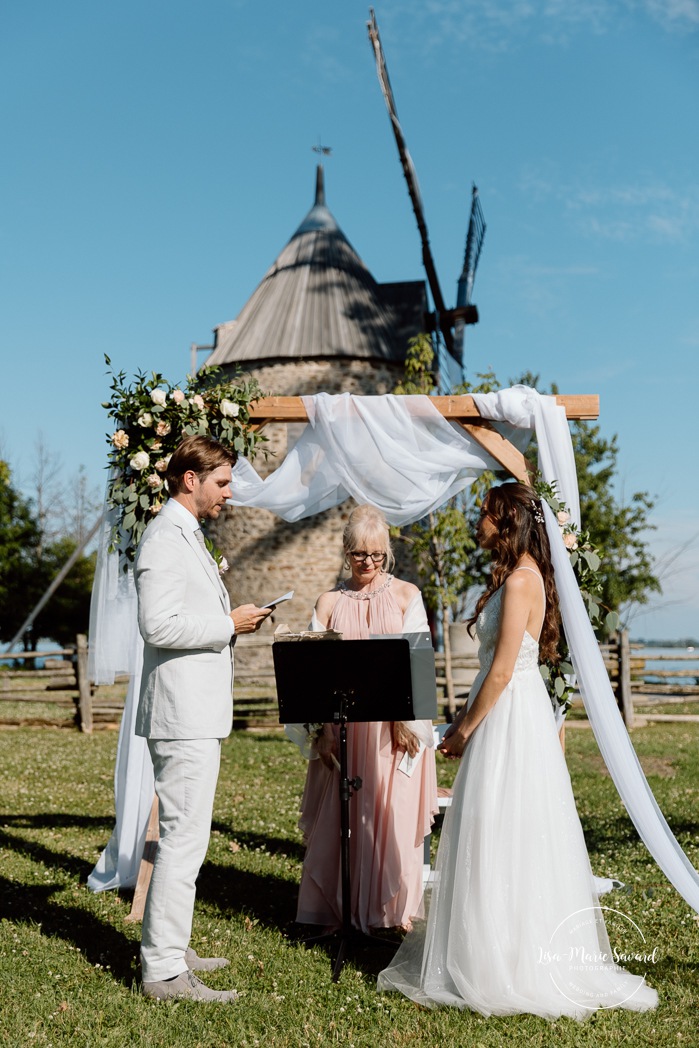 Outdoor wedding ceremony in front of windmill. Mariage à la Pointe-du-Moulin. Photographe mariage à Montréal. Pointe-du-Moulin wedding. Montreal wedding photographer.