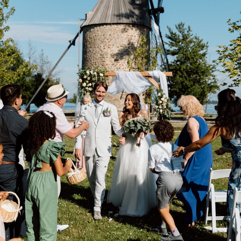 Outdoor wedding ceremony in front of windmill. Mariage à la Pointe-du-Moulin. Photographe mariage à Montréal. Pointe-du-Moulin wedding. Montreal wedding photographer.