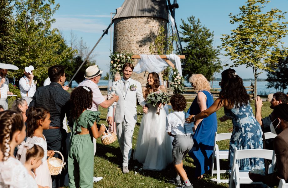 Outdoor wedding ceremony in front of windmill. Mariage à la Pointe-du-Moulin. Photographe mariage à Montréal. Pointe-du-Moulin wedding. Montreal wedding photographer.