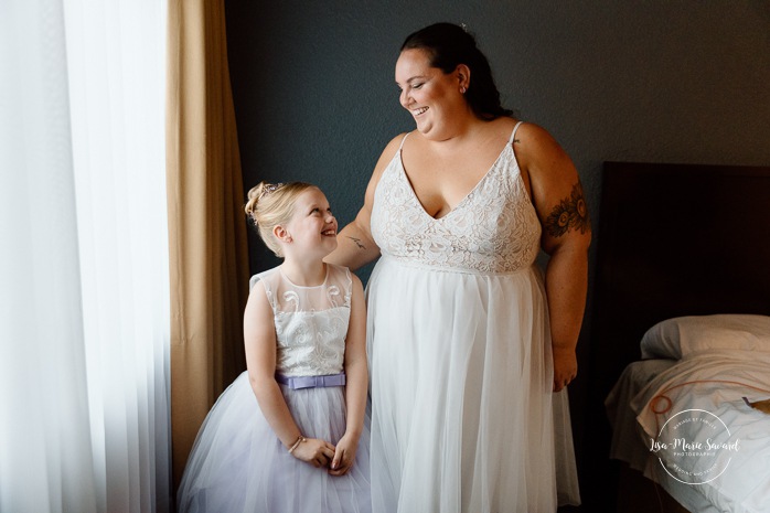 Bride getting ready in dark hotel room. Mariage avec deux femmes. Mariage LGBTQ+ au Saguenay-Lac-Saint-Jean. Photographe de mariage au Saguenay.