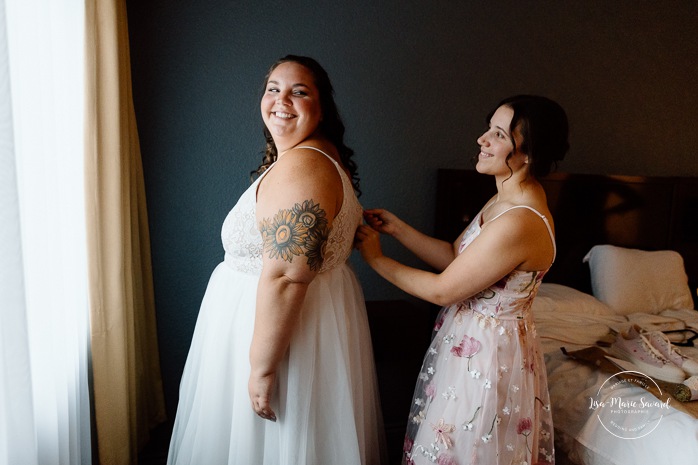 Bride getting ready in dark hotel room. Mariage avec deux femmes. Mariage LGBTQ+ au Saguenay-Lac-Saint-Jean. Photographe de mariage au Saguenay.