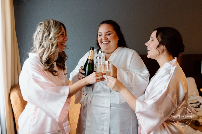 Bride getting ready in dark hotel room. Mariage avec deux femmes. Mariage LGBTQ+ au Saguenay-Lac-Saint-Jean. Photographe de mariage au Saguenay.