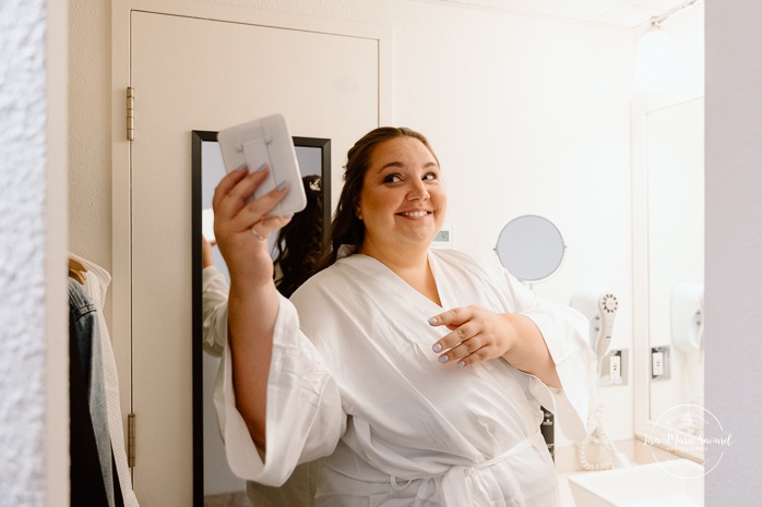 Bride getting ready in dark hotel room. Mariage avec deux femmes. Mariage LGBTQ+ au Saguenay-Lac-Saint-Jean. Photographe de mariage au Saguenay.