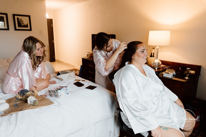 Bride getting ready in dark hotel room. Mariage avec deux femmes. Mariage LGBTQ+ au Saguenay-Lac-Saint-Jean. Photographe de mariage au Saguenay.