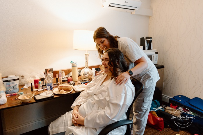 Bride getting ready in dark hotel room. Mariage avec deux femmes. Mariage LGBTQ+ au Saguenay-Lac-Saint-Jean. Photographe de mariage au Saguenay.