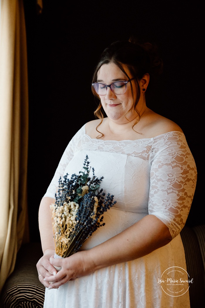 Bride getting ready in dark hotel room. Mariage avec deux femmes. Mariage LGBTQ+ au Saguenay-Lac-Saint-Jean. Photographe de mariage au Saguenay.