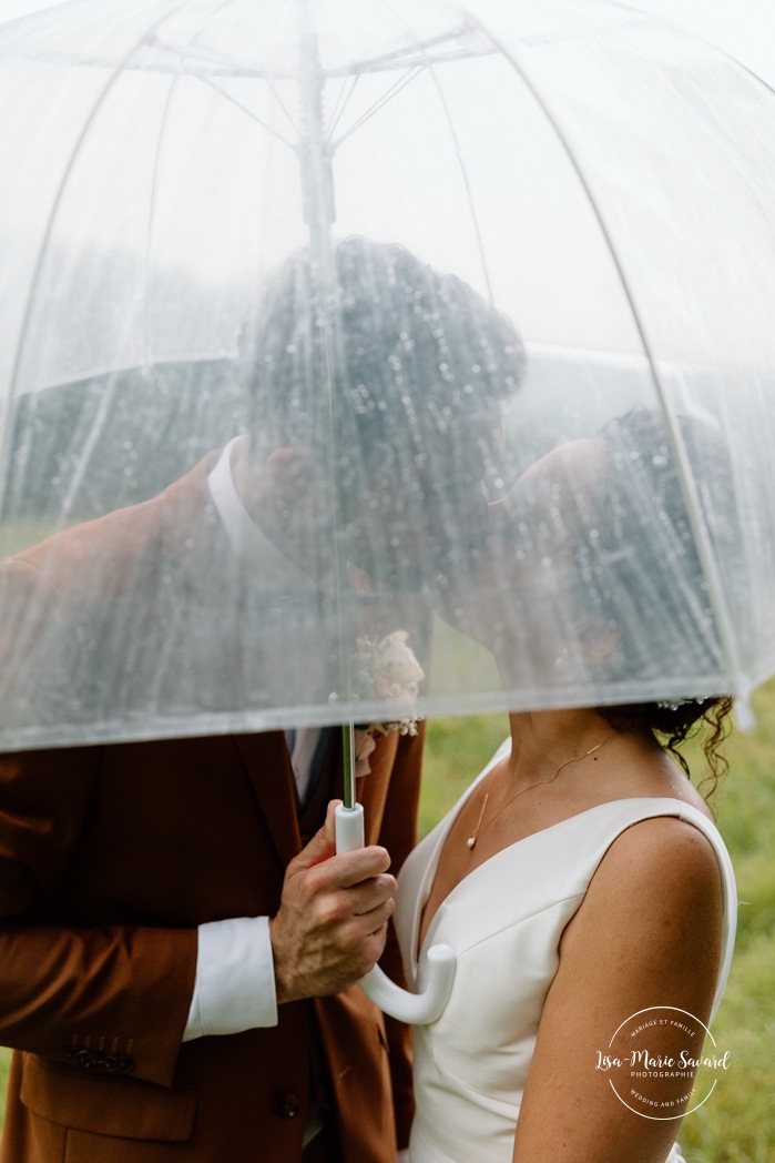 Rainy wedding photos. Wedding photos with umbrellas. Biracial wedding photos. Multicultural wedding photos. Mariage au Baluchon Éco-Villégiature. Auberge Le Baluchon. Photographe mariage Trois-Rivières.