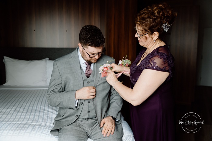 Groom getting ready with family in hotel room. Mariage à l'Auberge des Îles au Lac-Saint-Jean. Photographe de mariage au Saguenay-Lac-Saint-Jean.