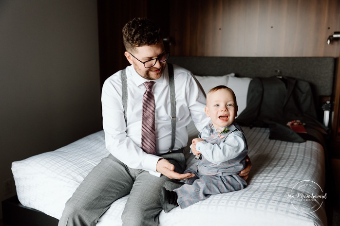 Groom getting ready with family in hotel room. Mariage à l'Auberge des Îles au Lac-Saint-Jean. Photographe de mariage au Saguenay-Lac-Saint-Jean.