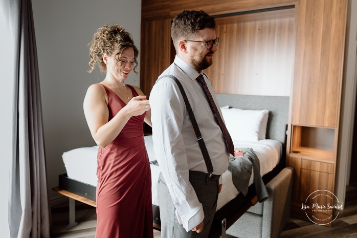Groom getting ready with family in hotel room. Mariage à l'Auberge des Îles au Lac-Saint-Jean. Photographe de mariage au Saguenay-Lac-Saint-Jean.