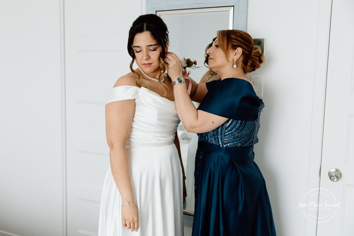 Bride getting ready with mother in hotel room. Mariage à l'Auberge des Îles au Lac-Saint-Jean. Photographe de mariage au Saguenay-Lac-Saint-Jean.