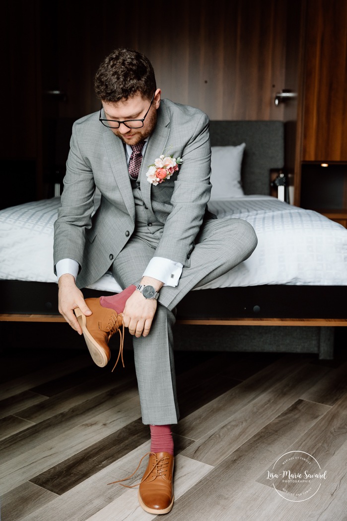 Groom getting ready with family in hotel room. Mariage à l'Auberge des Îles au Lac-Saint-Jean. Photographe de mariage au Saguenay-Lac-Saint-Jean.