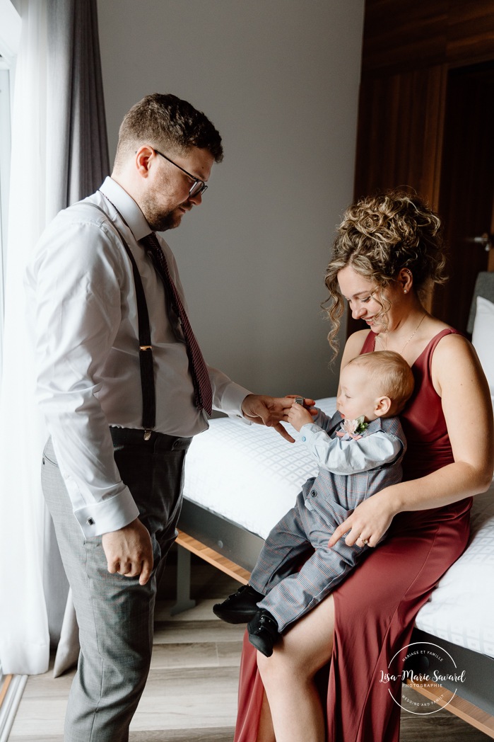 Groom getting ready with family in hotel room. Mariage à l'Auberge des Îles au Lac-Saint-Jean. Photographe de mariage au Saguenay-Lac-Saint-Jean.
