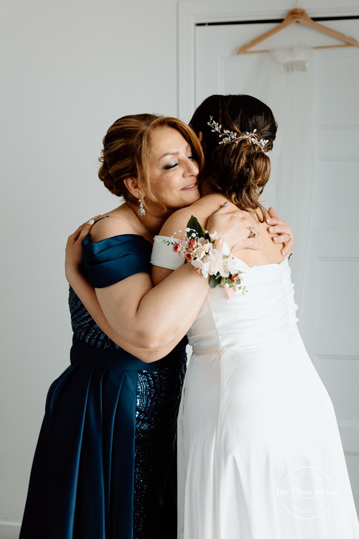 Bride getting ready with mother in hotel room. Mariage à l'Auberge des Îles au Lac-Saint-Jean. Photographe de mariage au Saguenay-Lac-Saint-Jean.