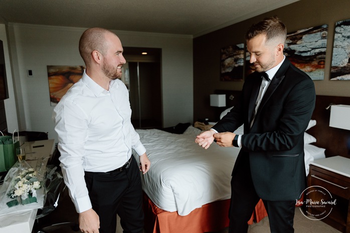 Groom getting ready with groomsmen in hotel room. Mariage à l'hôtel Delta Saguenay. Photographe mariage Saguenay-Lac-Saint-Jean