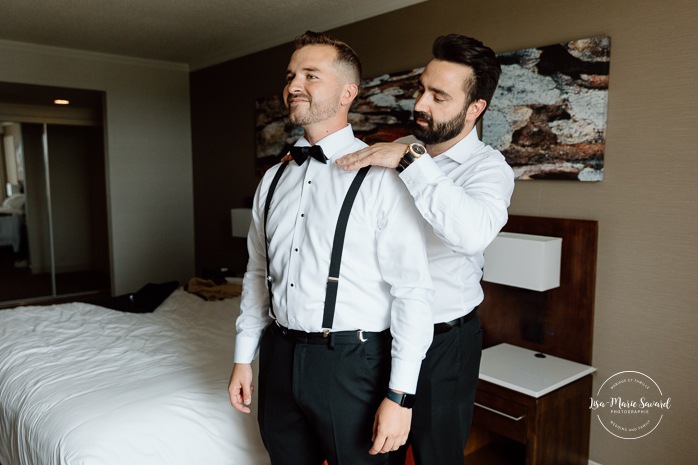 Groom getting ready with groomsmen in hotel room. Mariage à l'hôtel Delta Saguenay. Photographe mariage Saguenay-Lac-Saint-Jean