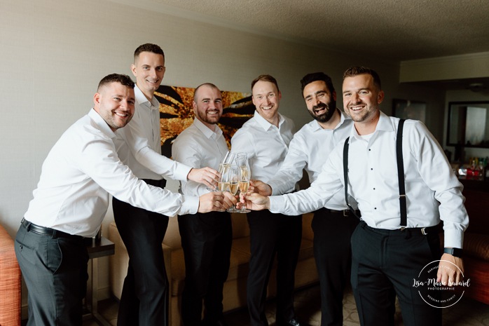 Groom getting ready with groomsmen in hotel room. Mariage à l'hôtel Delta Saguenay. Photographe mariage Saguenay-Lac-Saint-Jean