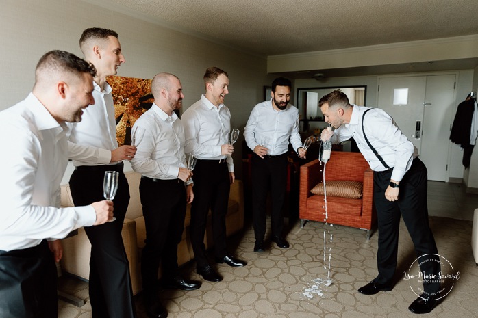Groom getting ready with groomsmen in hotel room. Mariage à l'hôtel Delta Saguenay. Photographe mariage Saguenay-Lac-Saint-Jean