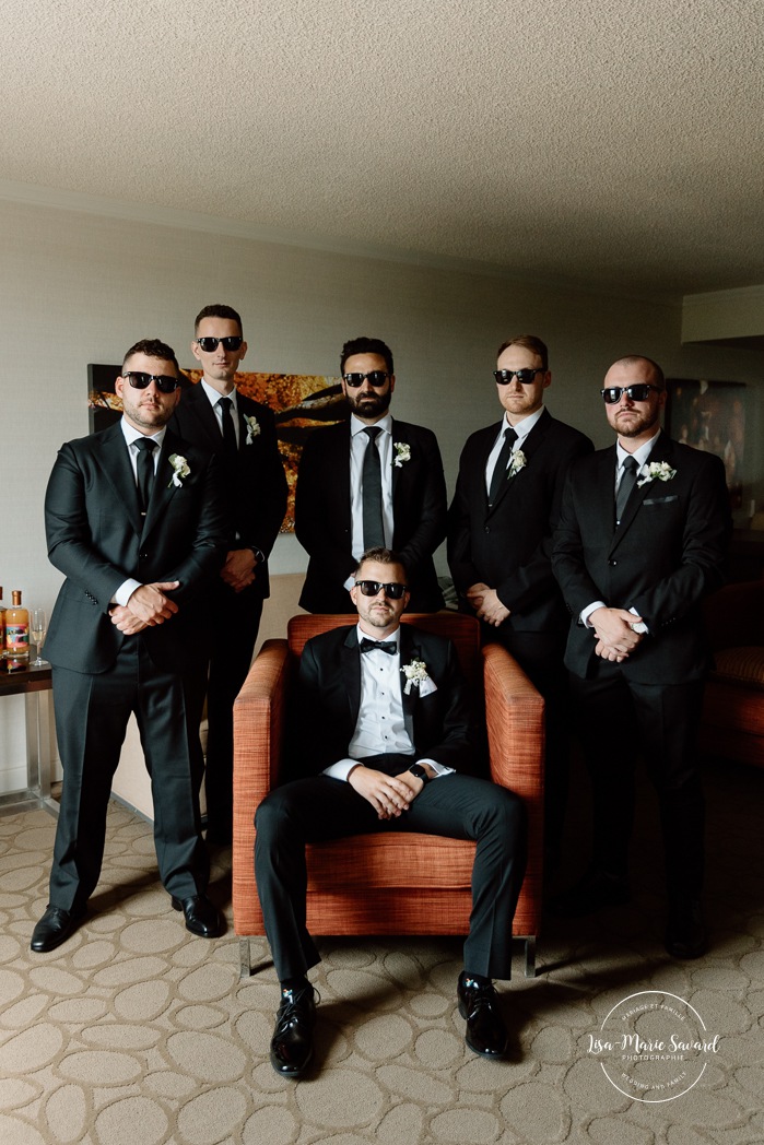 Groom getting ready with groomsmen in hotel room. Mariage à l'hôtel Delta Saguenay. Photographe mariage Saguenay-Lac-Saint-Jean