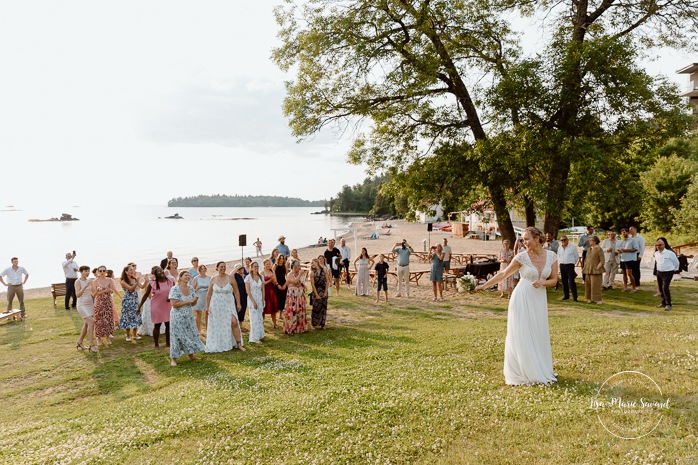 Bride throwing wedding bouquet. Mariage au bord du Lac-Saint-Jean. Auberge des Îles. Photographe mariage Saguenay-Lac-Saint-Jean