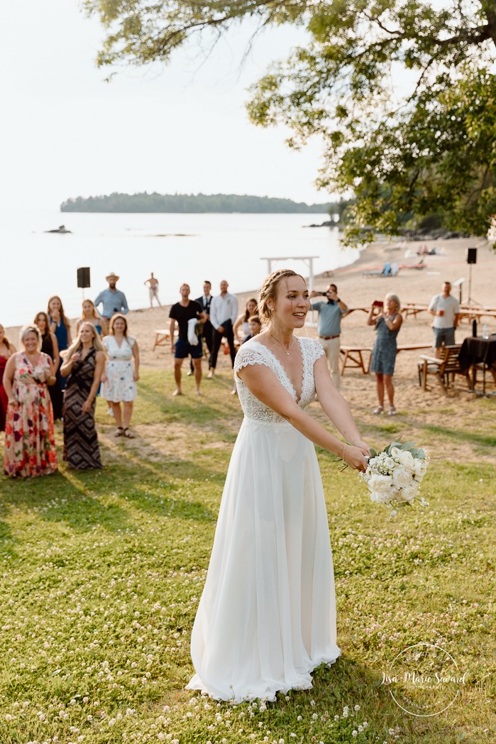 Bride throwing wedding bouquet. Mariage au bord du Lac-Saint-Jean. Auberge des Îles. Photographe mariage Saguenay-Lac-Saint-Jean