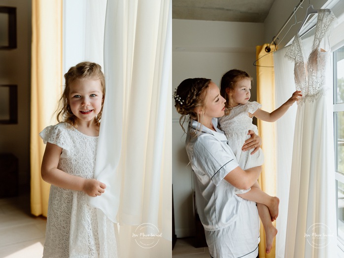 Wedding dresses hanging in front of window. Bride getting ready with bridesmaids. Mariage au bord du Lac-Saint-Jean. Auberge des Îles. Photographe mariage Saguenay-Lac-Saint-Jean