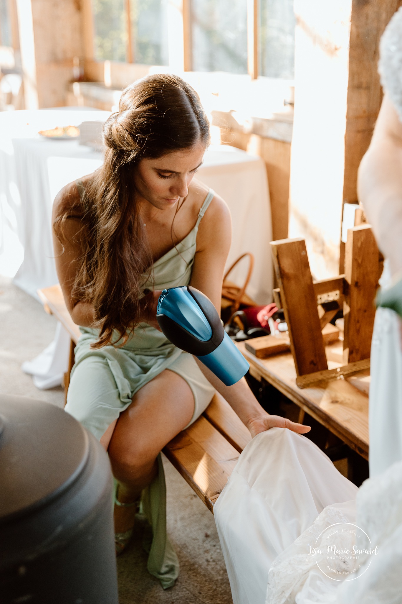 Bridesmaid drying bride's dress. Mariage à Le Pont Couvert de La Conception. Photographe mariage Laurentides. Le Pont Couvert wedding. Tremblant wedding photographer.