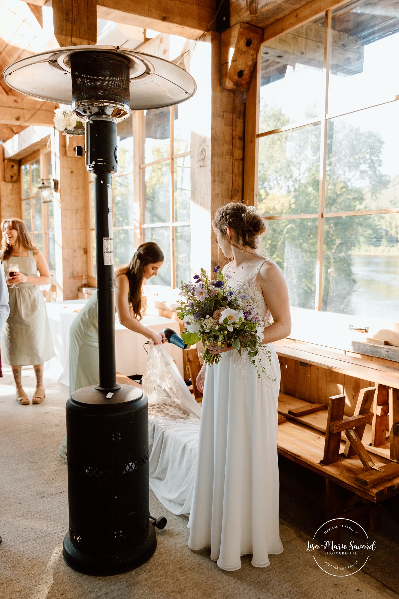 Bridesmaid drying bride's dress. Mariage à Le Pont Couvert de La Conception. Photographe mariage Laurentides. Le Pont Couvert wedding. Tremblant wedding photographer.