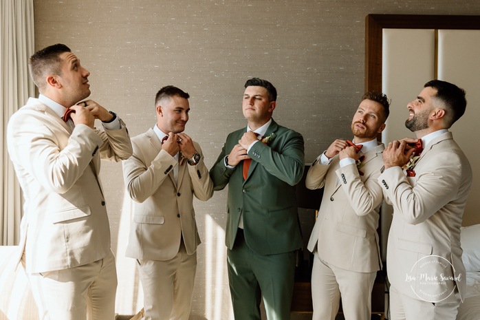 Groom getting ready with groomsmen in hotel room. Sheraton St-Hyacinthe. Mariage au Domaine St-Simon en automne. Photographe de mariage en Montérégie. Domaine St-Simon wedding.