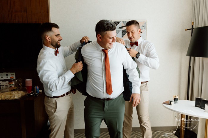 Groom getting ready with groomsmen in hotel room. Sheraton St-Hyacinthe. Mariage au Domaine St-Simon en automne. Photographe de mariage en Montérégie. Domaine St-Simon wedding.