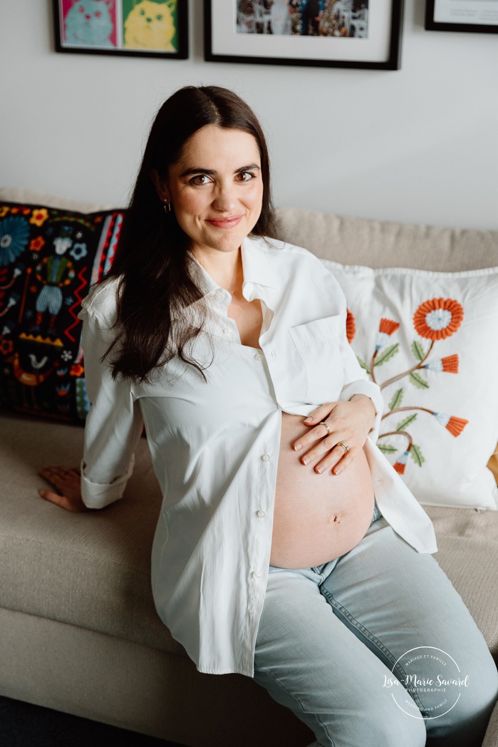 Expecting mother cradling her belly. In-home maternity photos. Living room maternity photos. Photos de maternité à la maison à Montréal. Photographe maternité Montréal. Montreal in-home maternity photos. Montreal maternity photographer.