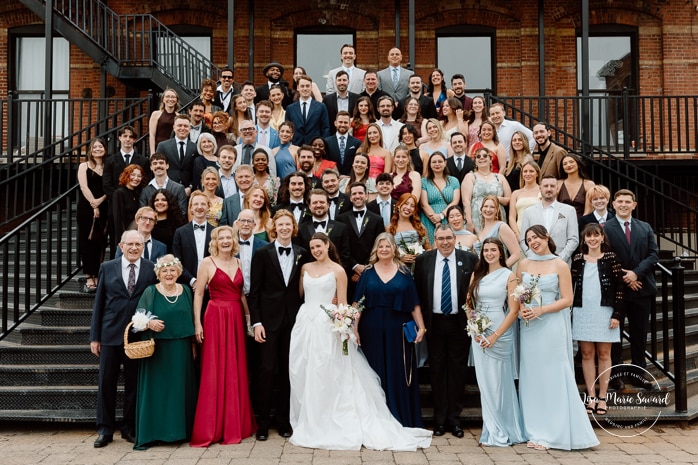 Large wedding group photo in staircase. Mariage à l'Espace Canal à Montréal. L'Ambroisie et Espace Canal. Photographe de mariage à Montréal. Espace Canal wedding. Montreal wedding photographer.
