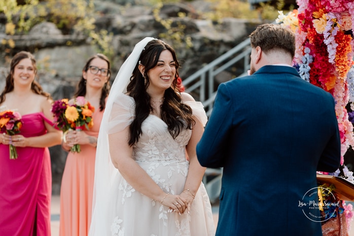 Outdoor wedding ceremony with floral arch. Colorful wedding ideas. Photographe de mariage au Saguenay. Photographe Saguenay-Lac-Saint-Jean. Mariage Pulperie de Chicoutimi. Jardin des Vestiges. Bâtiment 1912. Saguenay wedding photographer.