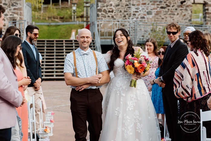 Outdoor wedding ceremony with floral arch. Colorful wedding ideas. Photographe de mariage au Saguenay. Photographe Saguenay-Lac-Saint-Jean. Mariage Pulperie de Chicoutimi. Jardin des Vestiges. Bâtiment 1912. Saguenay wedding photographer.