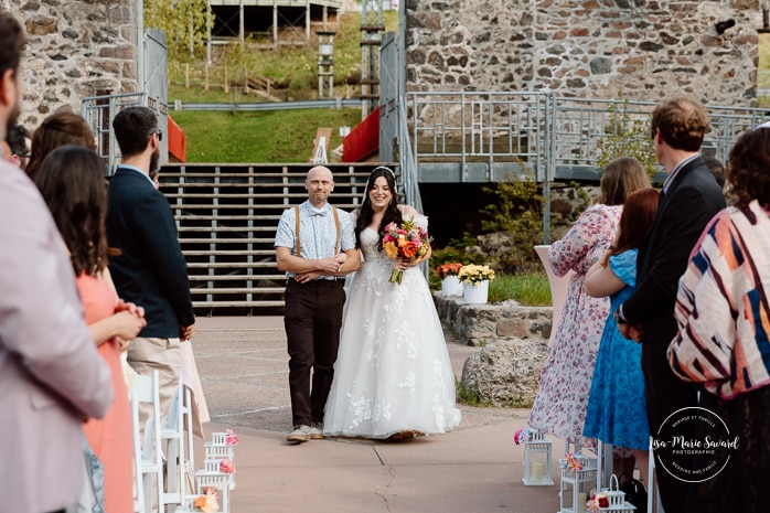 Outdoor wedding ceremony with floral arch. Colorful wedding ideas. Photographe de mariage au Saguenay. Photographe Saguenay-Lac-Saint-Jean. Mariage Pulperie de Chicoutimi. Jardin des Vestiges. Bâtiment 1912. Saguenay wedding photographer.