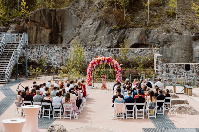 Outdoor wedding ceremony with floral arch. Colorful wedding ideas. Photographe de mariage au Saguenay. Photographe Saguenay-Lac-Saint-Jean. Mariage Pulperie de Chicoutimi. Jardin des Vestiges. Bâtiment 1912. Saguenay wedding photographer.