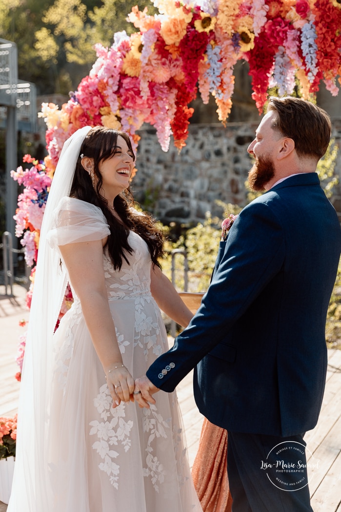 Outdoor wedding ceremony with floral arch. Colorful wedding ideas. Photographe de mariage au Saguenay. Photographe Saguenay-Lac-Saint-Jean. Mariage Pulperie de Chicoutimi. Jardin des Vestiges. Bâtiment 1912. Saguenay wedding photographer.