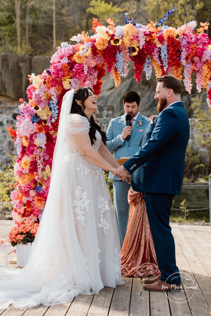 Outdoor wedding ceremony with floral arch. Colorful wedding ideas. Photographe de mariage au Saguenay. Photographe Saguenay-Lac-Saint-Jean. Mariage Pulperie de Chicoutimi. Jardin des Vestiges. Bâtiment 1912. Saguenay wedding photographer.